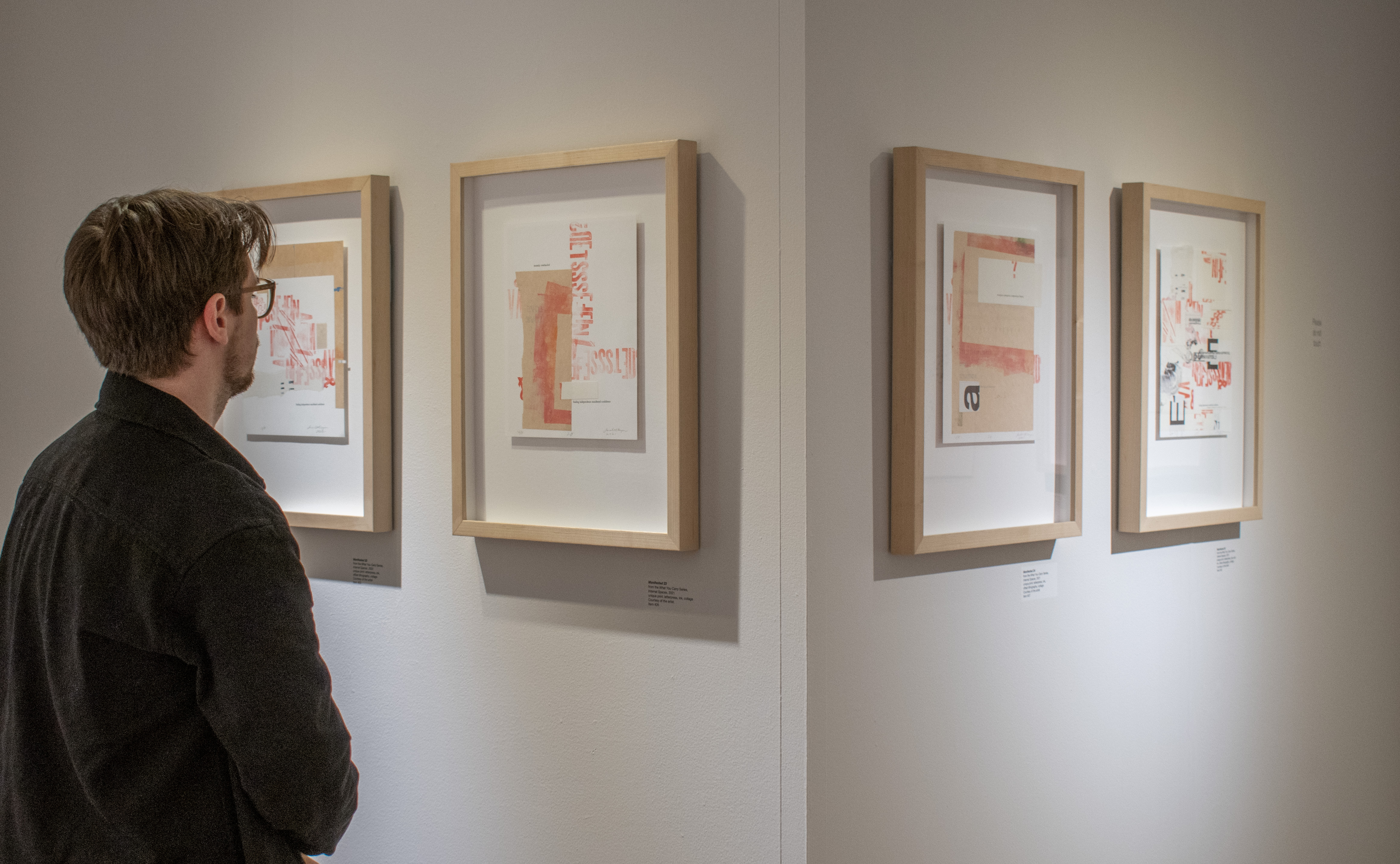 A photograph showing a gallery guest looking at the displayed pieces