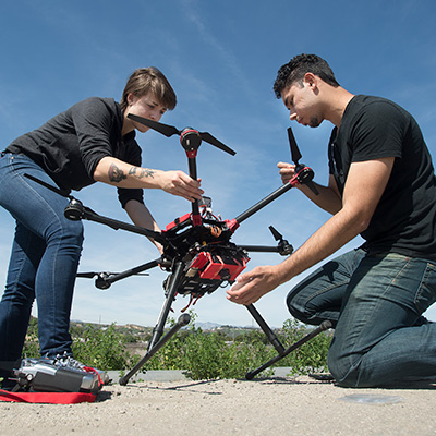 two students working with a drone