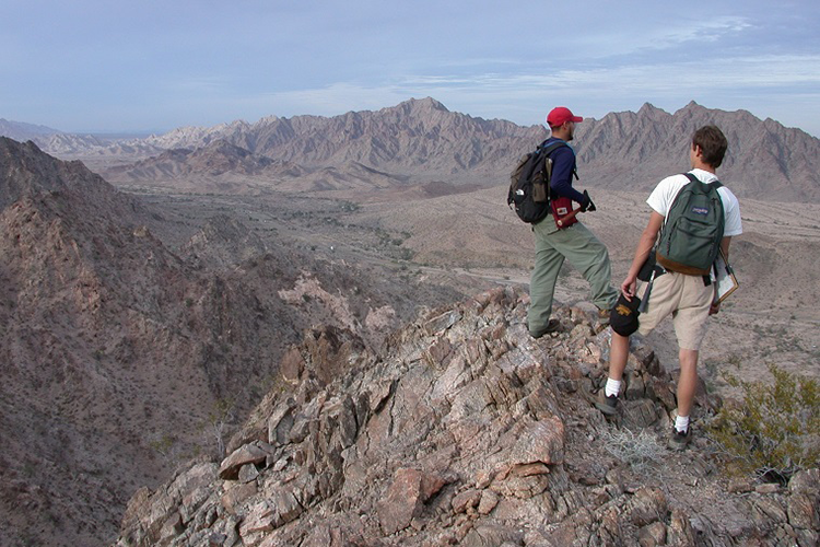 two students in a field work on a mountaintop
