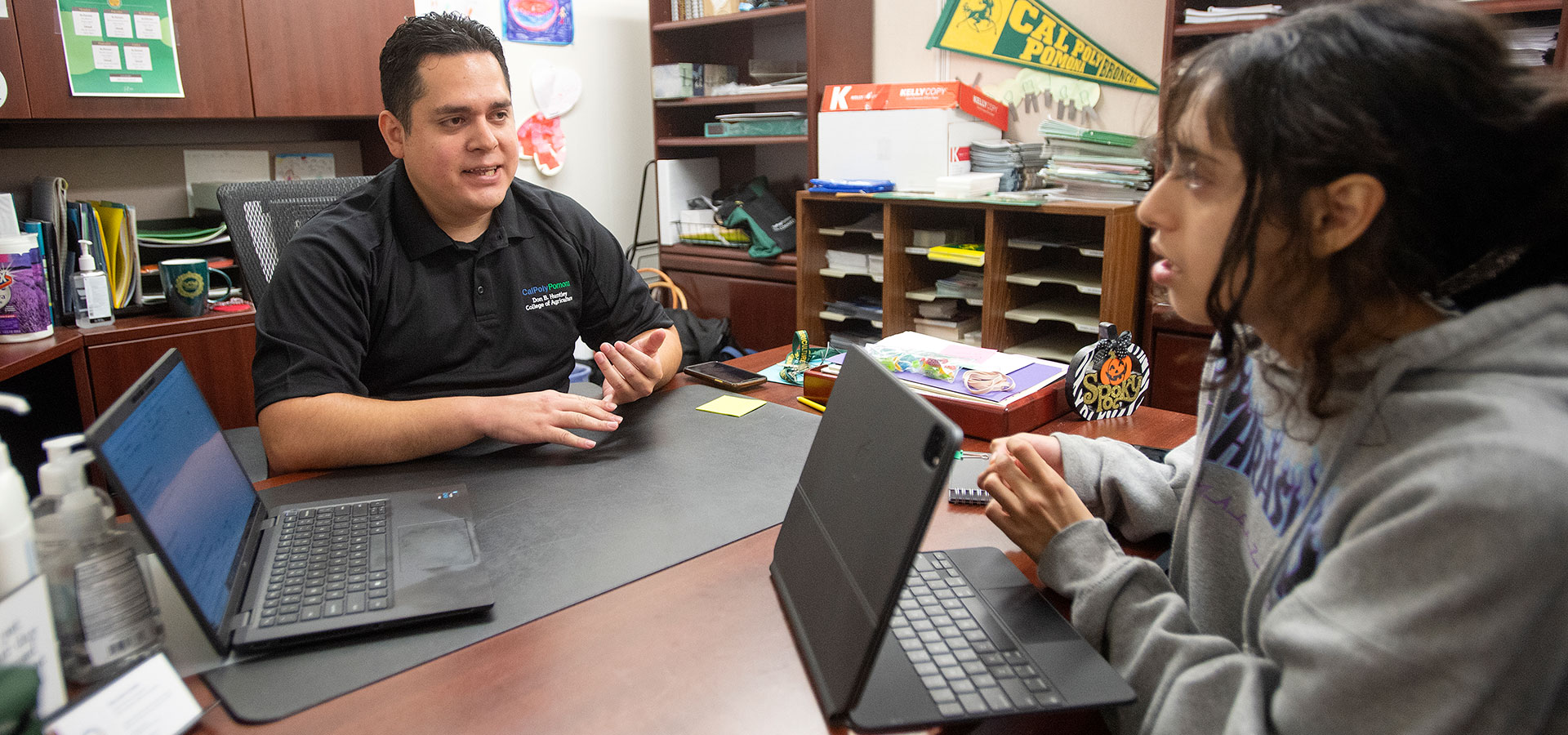A student speaks with an academic advisor in an office.