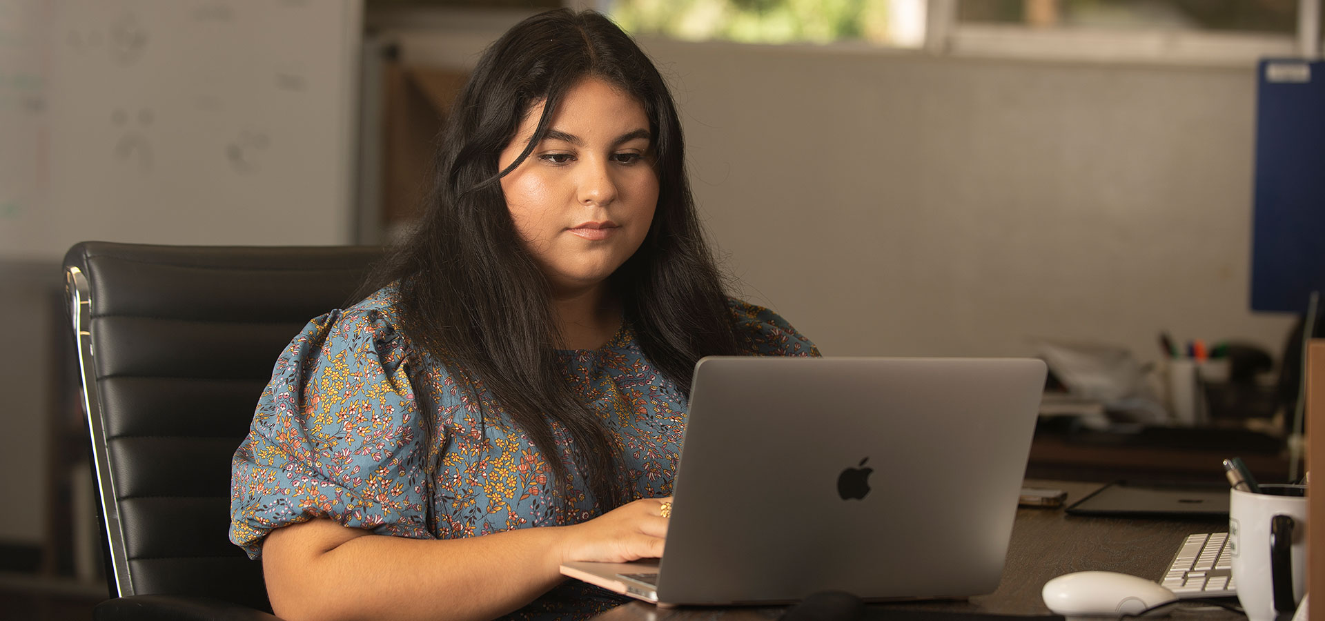 A girl sits at a table with a laptop