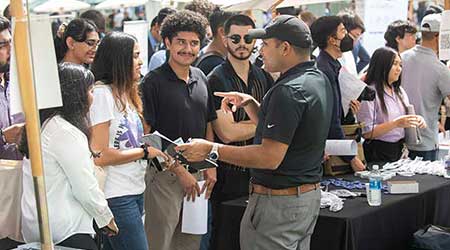 A group of students talk to recruiters during a campus career fair.